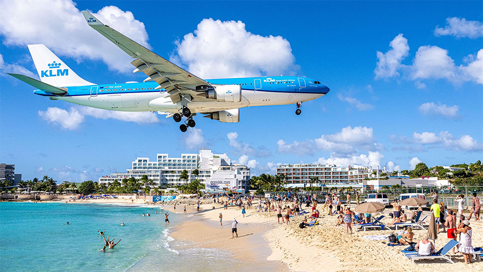 Tourists gather at Maho Beach to photograph a low-flying aircraft 