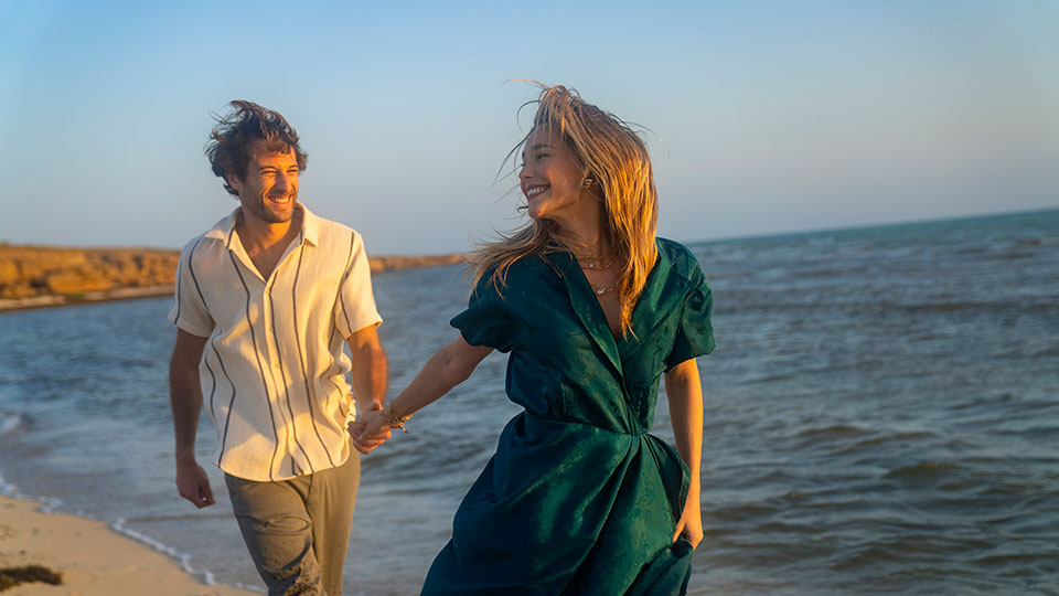 A couple standing on the beach and reach out to hold each others hand. in the Farasan Islands
